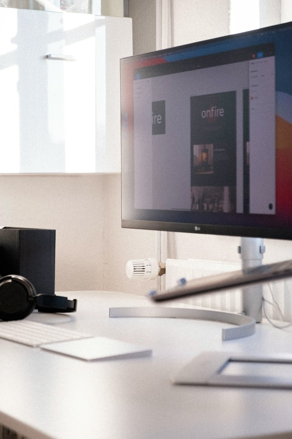 Scrivania moderna con computer che mostra un design di sito web e cuffie.